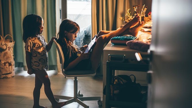 Two children absorbed in tablets in a sunlit room